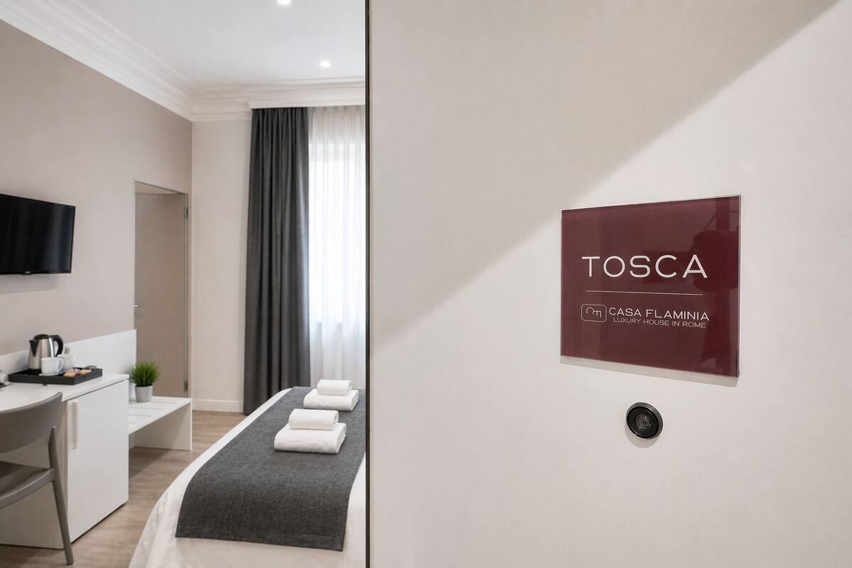 A modern hotel room with a bed, a desk, a TV, and a sign indicating it's a luxury house in Rome.