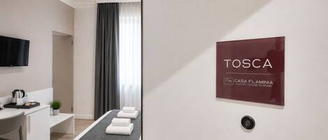 A modern hotel room with a bed, a desk, a TV, and a sign indicating it's a luxury house in Rome.
