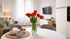 A modern living room with a white table, a vase of red tulips, a candle, and a bowl of strawberries. - Casa Flaminia (Rome)