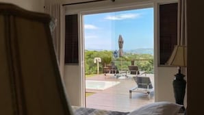 A hotel room with a bed, a ceiling fan, a view of an outdoor pool and lounge chairs, and a large window. - Top De Buzios Boutique Hotel & Spa (Búzios)