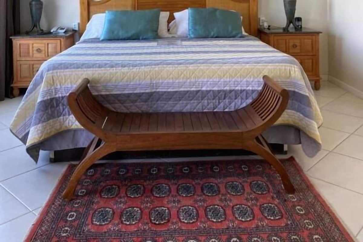 Ein Schlafzimmer mit einem Bett, zwei Nachttischen, einem Deckenventilator, dekorativen Wandspiegeln und einem gemusterten Teppich.