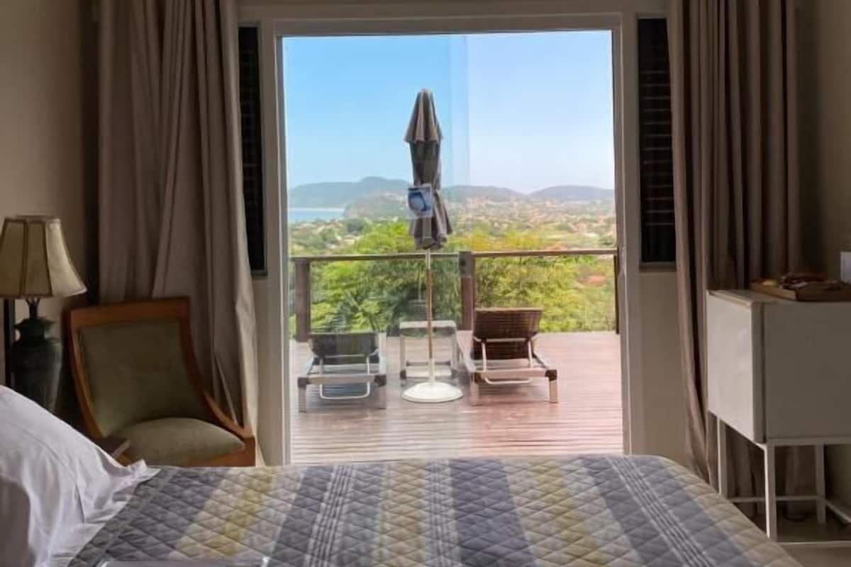 Ein Hotelzimmer mit Bett, Stuhl, Schreibtisch und einem Balkon mit Landschaftsblick.