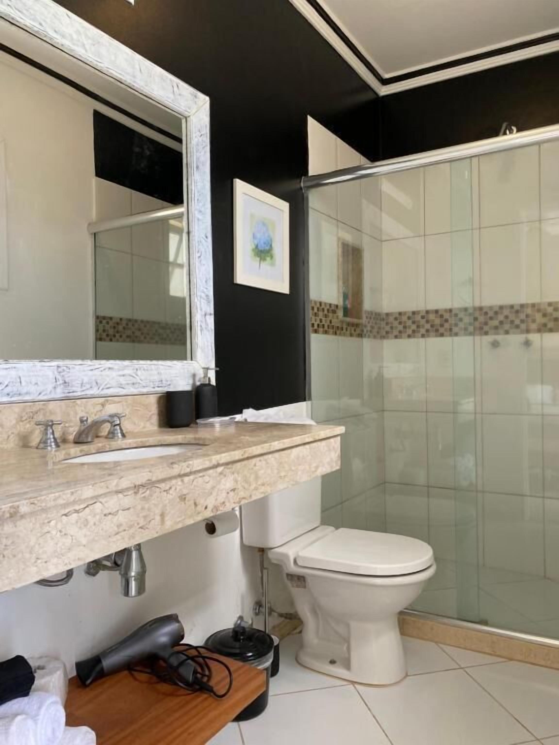Ein modernes Badezimmer mit einem мраморным Waschbecken, einer Toilette und einer Duschkabine aus Glas.