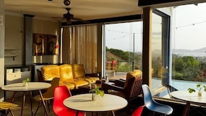 A modern interior with a dining area featuring red and blue chairs, a yellow sofa, and a ceiling fan. - Top De Buzios Boutique Hotel & Spa (Búzios)