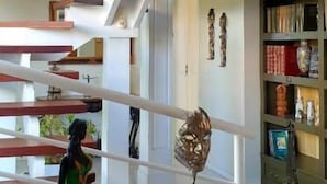 A modern interior with a staircase, a small table with a potted plant, and a bookshelf with various items. - Top De Buzios Boutique Hotel & Spa (Búzios)