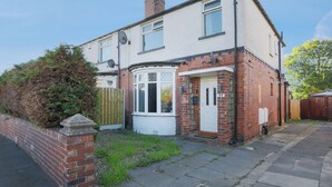 A two-story house with a brick facade, a white front door, and a small front garden. - Stylish 3BR House | Perfect for Contrators & Extended Stays (Sheffield)