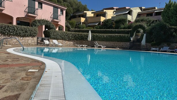A clear swimming pool with lounge chairs and a stone pathway. - BouganVilla - Two-room apartment with sea view in Badesi (Badesi)
