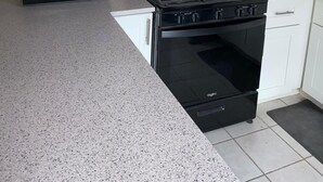 A kitchen with white cabinets, a black stove, a toaster, and a microwave.