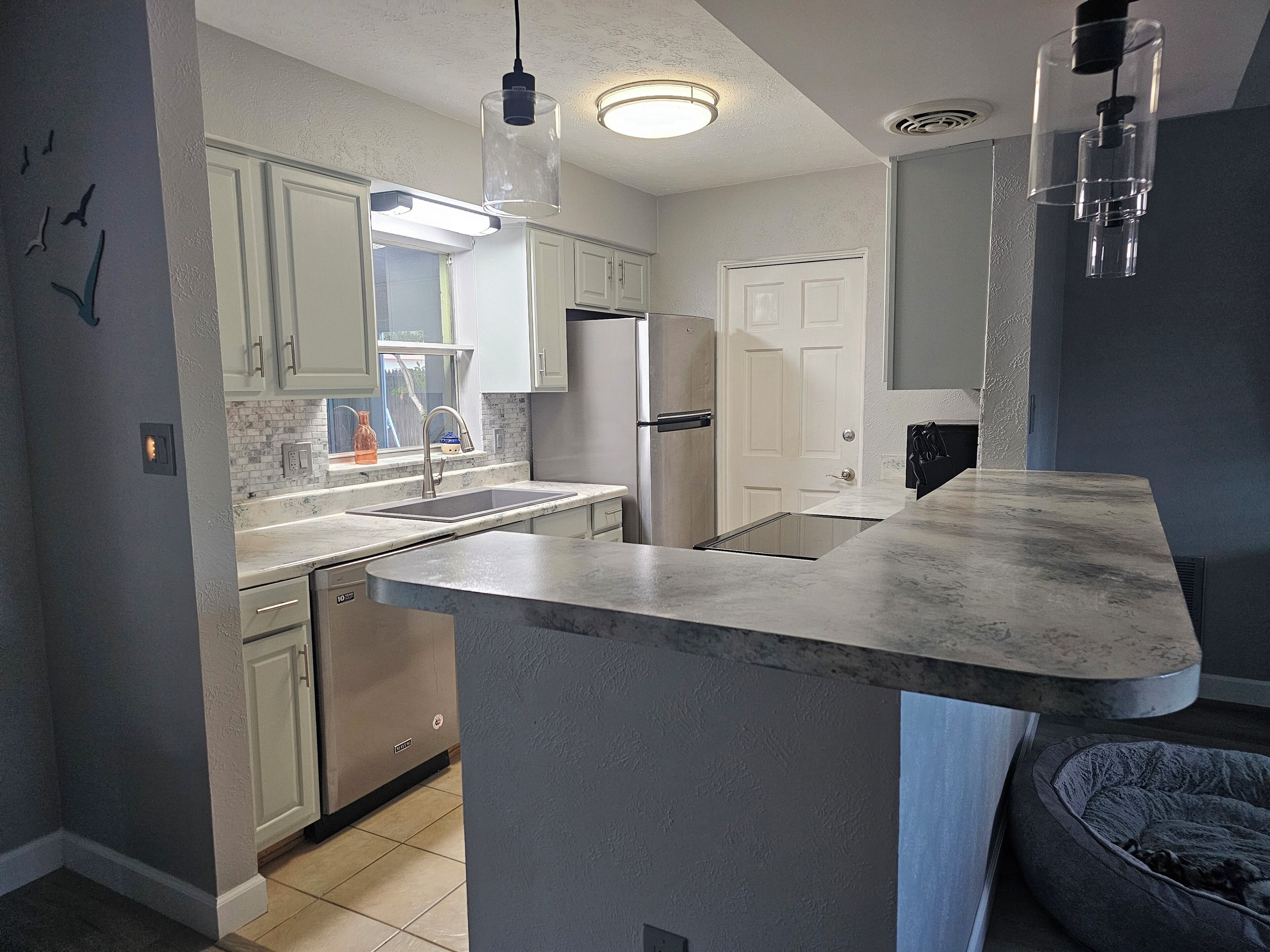 A modern kitchen with white cabinets, a built-in island, and a gray countertop.