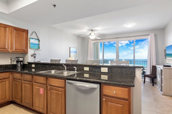 A modern kitchen with granite countertops, wooden cabinets, and a dishwasher.