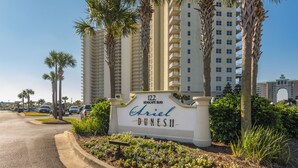 A sign for 'Ariel Dunes II' with a view of tall buildings and palm trees.