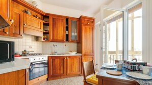 Een keuken met houten kasten, een fornuis en een eethoek met een tafel en stoelen.