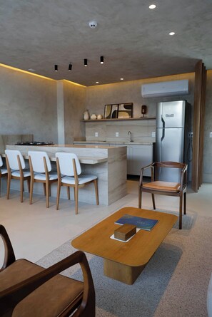 A modern kitchen with a built-in refrigerator, a dining area with chairs, and a coffee table.