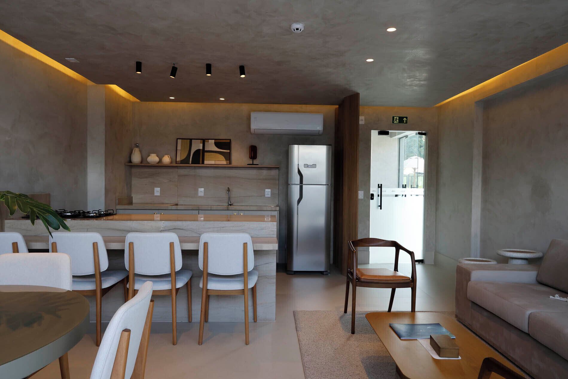 A modern kitchen with a refrigerator, dining chairs, a sofa, and a coffee table.