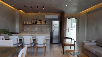 A modern kitchen with a refrigerator, dining chairs, a sofa, and a coffee table.