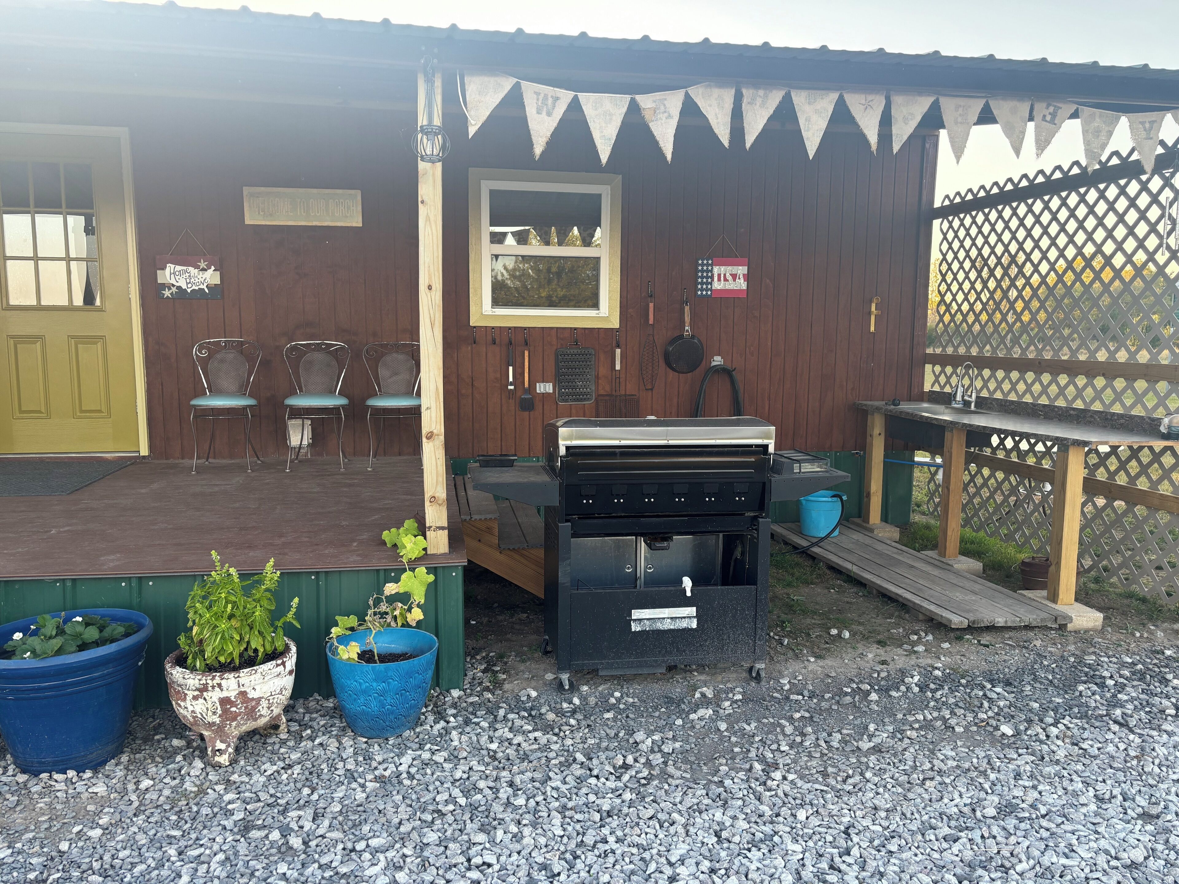 Eine Holzterrasse mit Grill, Topfpflanzen und Gartenmöbeln.