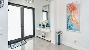 A modern hallway with a white console table, a large mirror, and a colorful abstract painting.