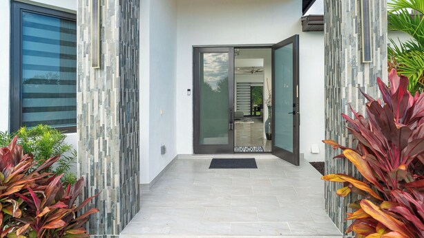 A modern entrance with a glass door, a stone wall, and a tiled floor.