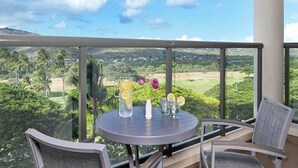 En balkon med et bord dækket til to, der giver frit udsyn over et frodigt landskab.