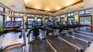 Et fitnessrum med flere løbebånd, hvert udstyret med digital skærm, samt store vinduer der giver naturligt lys og udsigt til det fri.