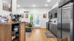 Eine moderne Küche mit einem eingebauten Kühlschrank, Holzschränken und einem grünen Sofa im angrenzenden Wohnbereich.