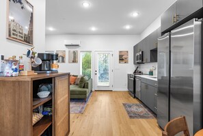 A modern kitchen with a built-in refrigerator, wooden cabinets, and a green sofa in the adjacent living area. - Rocky Top Rowhouse :: Modern Townhouse -- Sleeps 4! Walk to Neyland & DT Knox! (Knoxville)