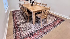 A dining area with a wooden table and chairs, a patterned rug, a pendant light, and a painting on the wall. - Spacious Roanoke Retreat (Roanoke)