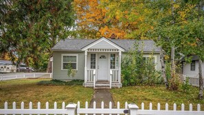 A small, single-story house with a front porch, a white picket fence, and a mailbox. - Charming Downtown Home, Walk to CDA Shops&Eateries (Coeur d'Alene)