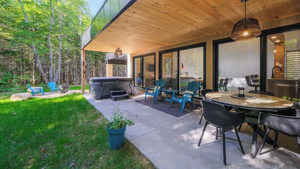 An outdoor patio with a grill, seating, and a view of the forest. - Spa & forest in St-Donat/Tremblant - Nature and relaxation getaway (Notre-Dame-de-la-Merci)