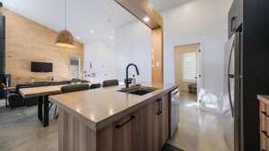 A modern kitchen with a central island, wooden cabinetry, a built-in sink, and a stainless steel refrigerator. - Spa & forest in St-Donat/Tremblant - Nature and relaxation getaway (Notre-Dame-de-la-Merci)