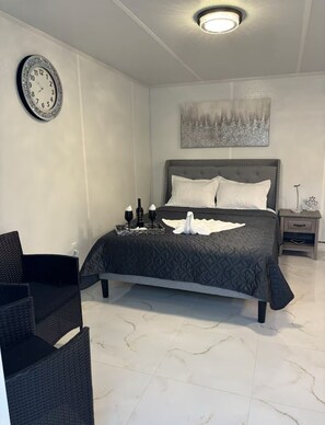 A modern bedroom with a large bed, a wall clock, a painting, and a nightstand with a lamp. - Tampa Dream Getaway "A (Tampa)