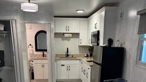 A modern kitchen with white cabinets, a stainless steel refrigerator, and a marble floor. - Tampa Dream Getaway "A (Tampa)