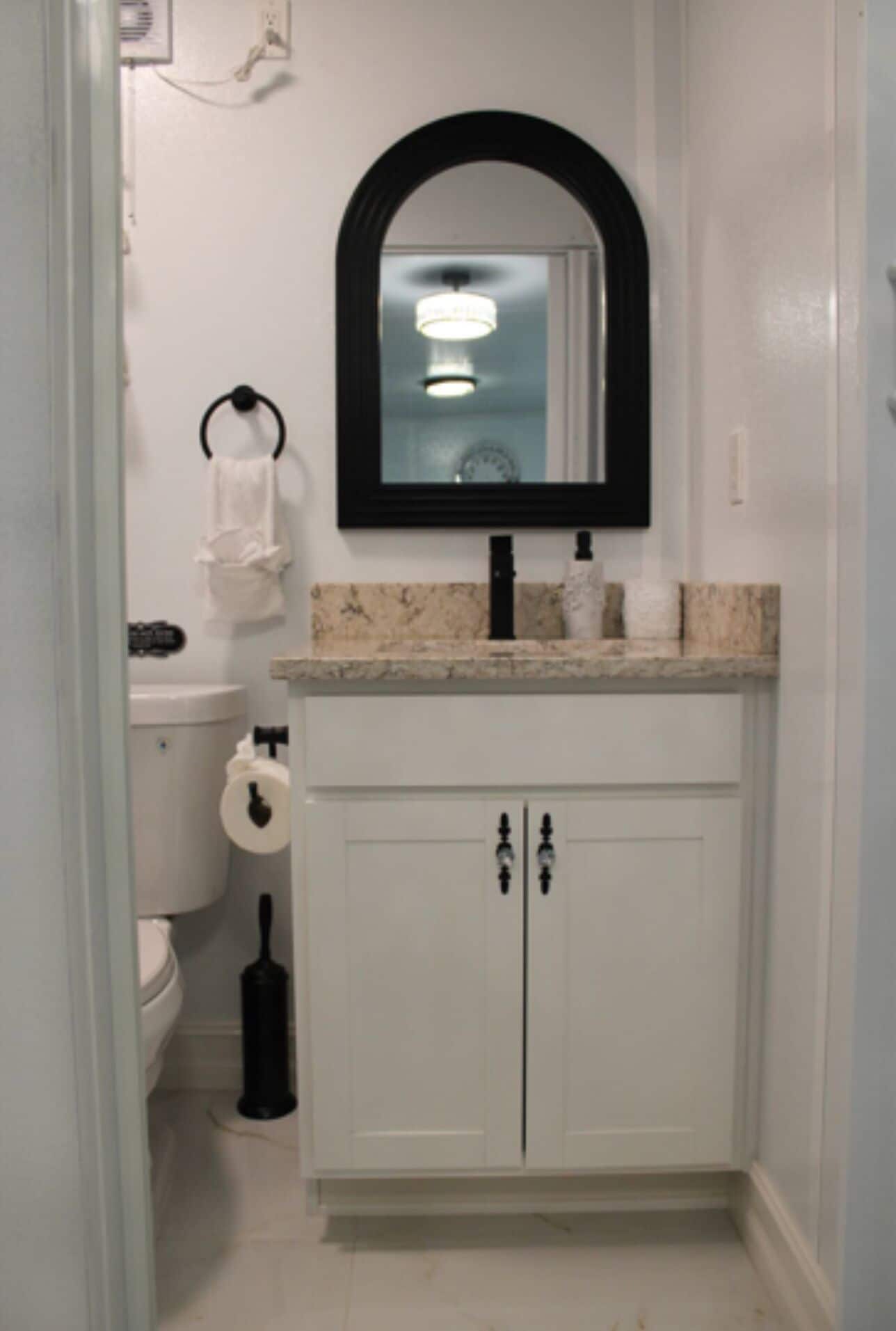 A bathroom with a white sink, a mirror above it, a toilet, and a cabinet below.
