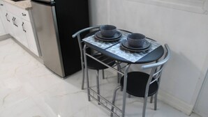 A compact kitchen with a stainless steel refrigerator, a small table with two chairs, and a tiled floor. - Tampa Dream Getaway "A (Tampa)