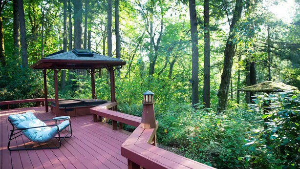 Une terrasse en bois avec un gazebo, un jacuzzi et un fauteuil de relaxation.