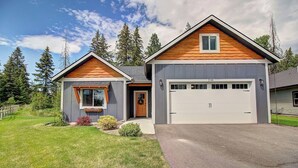 Ein zweistöckiges Haus mit Garage, ein Veranda und einem gepflegten Rasen.