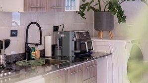 A modern kitchen with a built-in washing machine, a coffee machine, and a potted plant. - Bright Room with Private Bathroom & Balcony Ocean View (San Felipe)