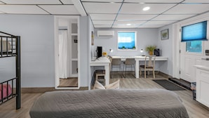A modern bedroom with a large bed, a desk with two chairs, a computer, and a window with a view. - Modern Duplex, Sleeps 10, Dog Friendly + Fenced Yard, Full Kitchen & Kitchenette (Galveston)