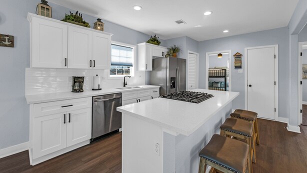 A modern kitchen with white cabinetry, stainless steel appliances, and a central island. - Modern Duplex, Sleeps 10, Dog Friendly + Fenced Yard, Full Kitchen & Kitchenette (Galveston)