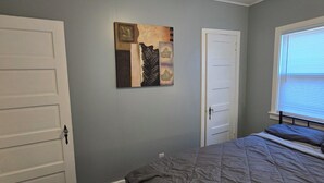 Quarto com cama, ventilador de teto, janela com persianas e porta.