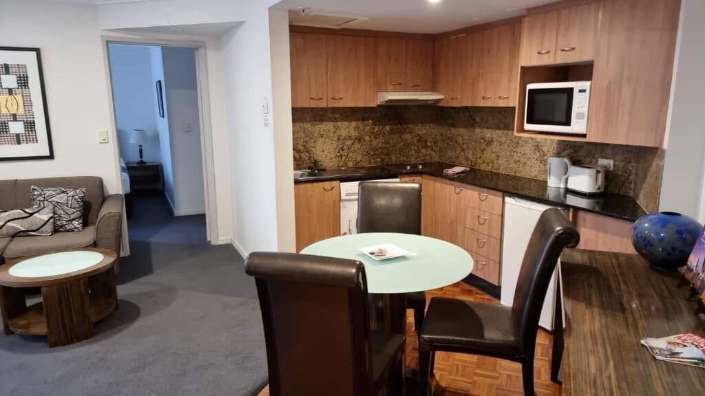 A compact living space with a kitchenette, a dining area with a round table and chairs, and a sofa with a small coffee table.