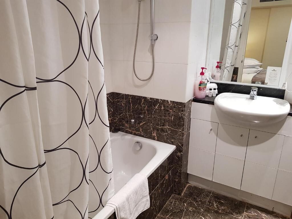 A bathroom with a bathtub, a white sink, and a shower.