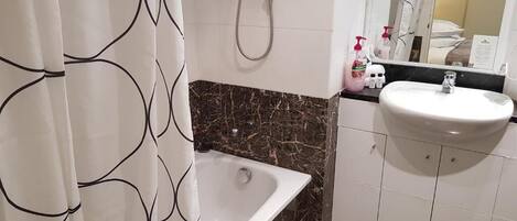 A bathroom with a bathtub, a white sink, and a shower.
