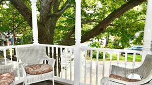 A covered porch with wicker furniture and a white railing. - Rehoboth Beach House Dog OK Hot Tub Sleeps 12 Clean and Convient (Rehoboth Beach)