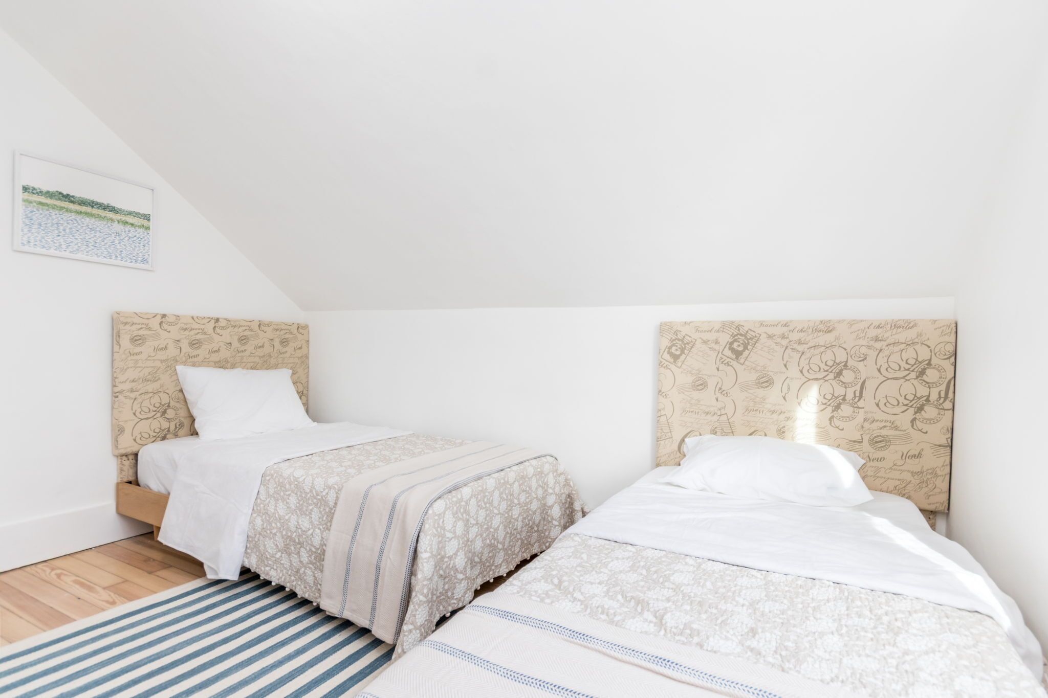 A bedroom with two beds, a striped rug, and a wall with a map pattern.