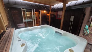 Ein Whirlpool mit Holzterrasse und Glastür zum Innenbereich.