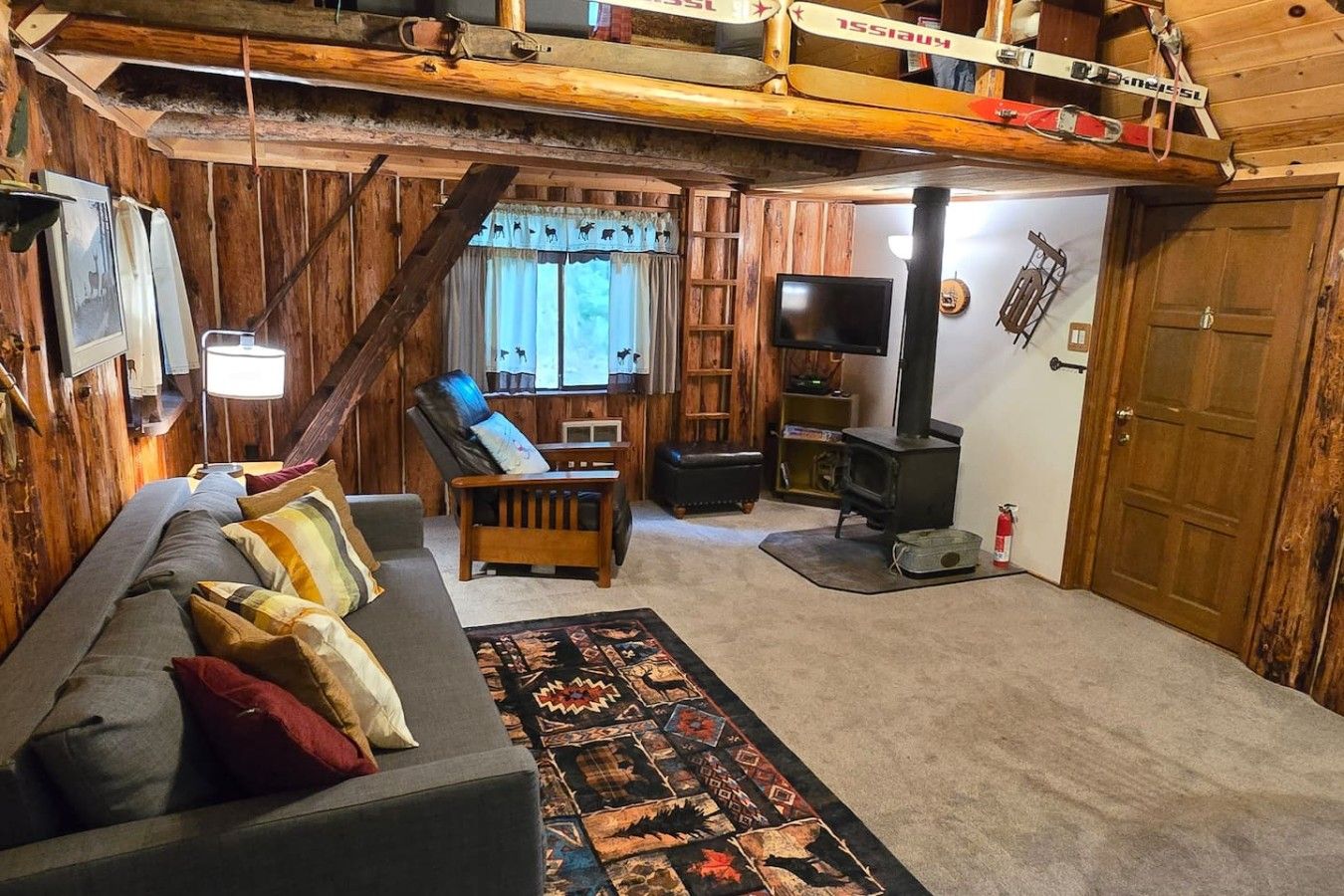 Uma sala de estar acolhedora com um sofá, uma poltrona, uma televisão e uma lareira.