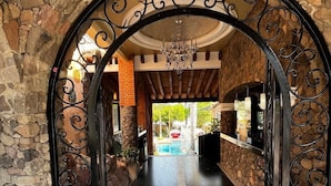 Ein Eingang zu einem Boutique-Resort mit einem Steinkubus, einer Chandelüster und einem Pool im Hintergrund.