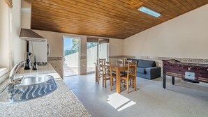 A kitchen with a sink, stove, and dining area with chairs and a table. - Casal do Porto - A vacation retreat (Lourido)