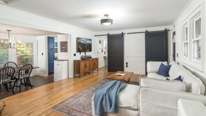 A spacious living room with a large sofa, a coffee table, and a dining area with chairs and a table.